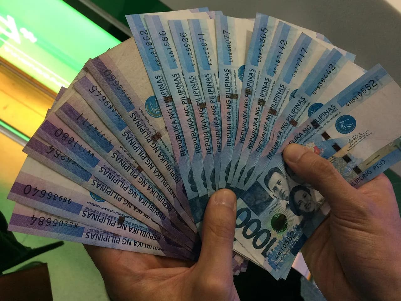 A hand fanning out Philippine 1,000-peso bills