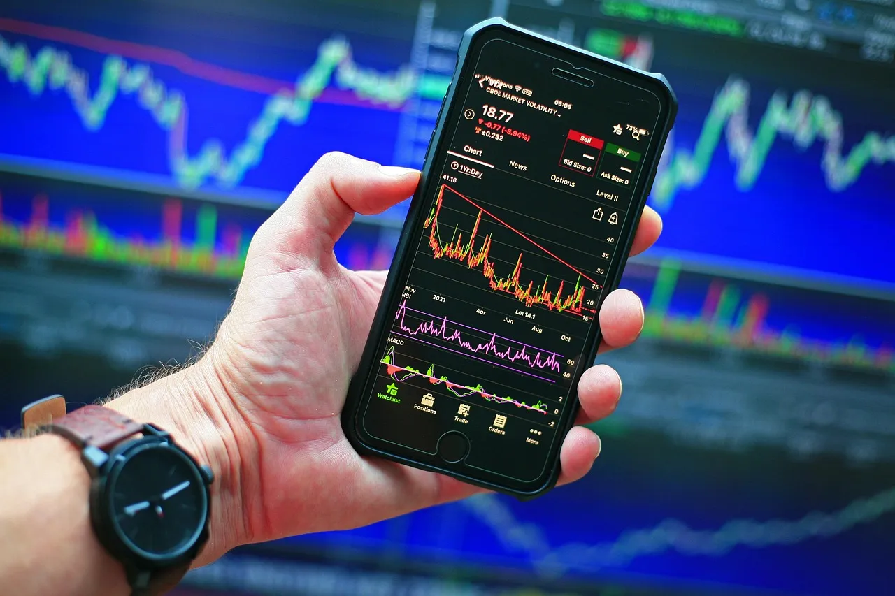 A hand holding a smartphone showing a stock chart
