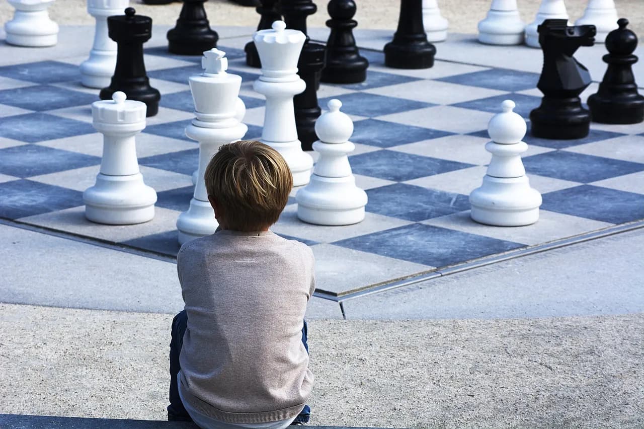A child sitting in front of a giant chessboard